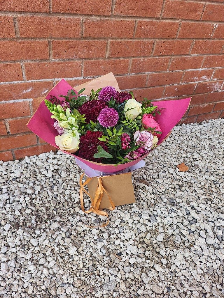 Gift bouquet of burgundy chrysanthemums, cream roses and lilac pompons in a kraft box with gold ribbon