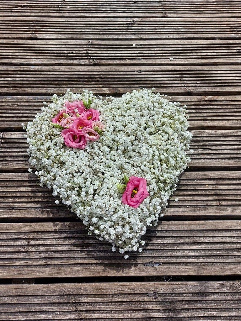 Heart of white gypsophila with pink lisianthus on weathered boards