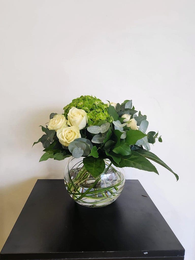 Cream roses, lime hydrangea and eucalyptus in a clear glass bowl vase