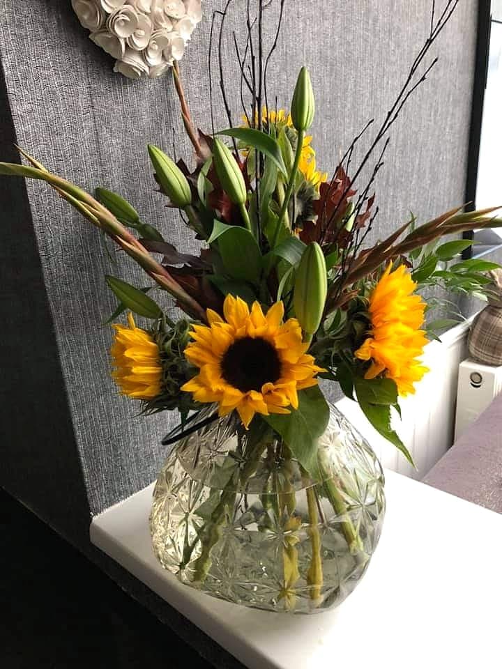 Sunflowers and lily buds in a cut-glass vase on a windowsill
