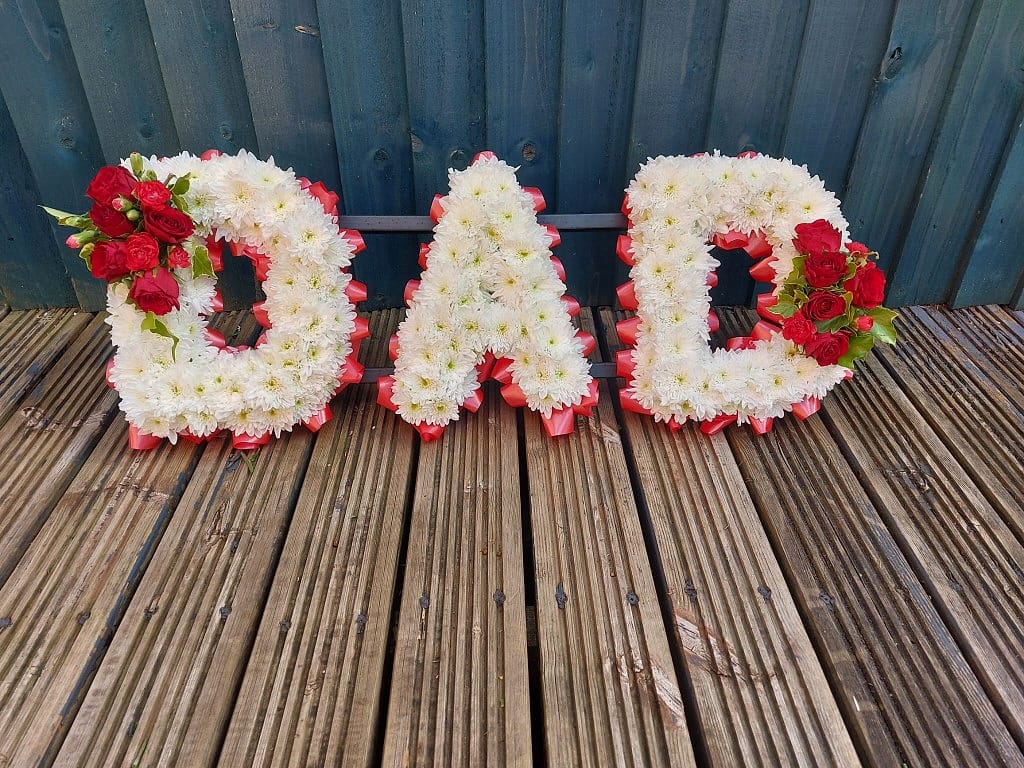 Letter tribute of white chrysanthemums and red roses spelling out one simple word